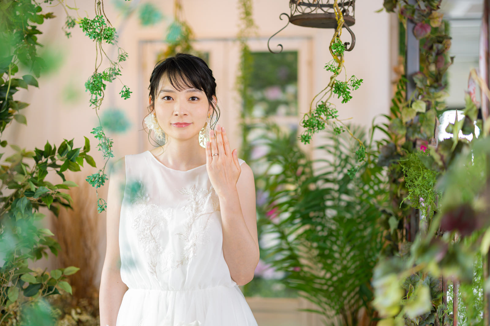 白いウェディングドレスを着た女性が結婚指輪を見せているポーズ［モデル：たけべともこ］