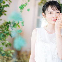 結婚指輪を見せて幸せいっぱいの花嫁、緑の背景でウェディングドレス姿の写真