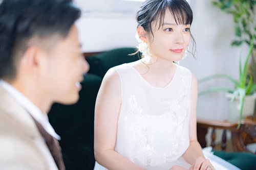 ウェディングドレスの新婦と新郎がにこやかに話を聞く