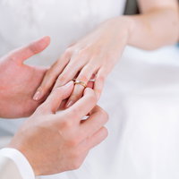 白いドレス姿で左の薬指に結婚指輪をはめる瞬間の写真