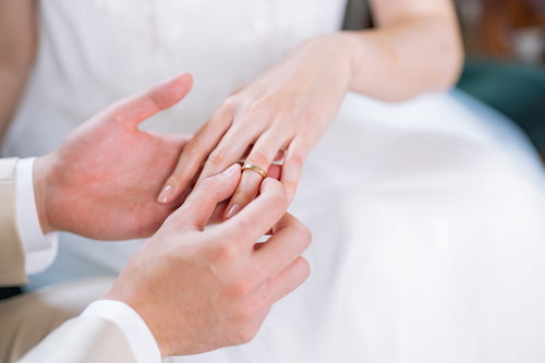 白いドレス姿で左の薬指に結婚指輪をはめる瞬間