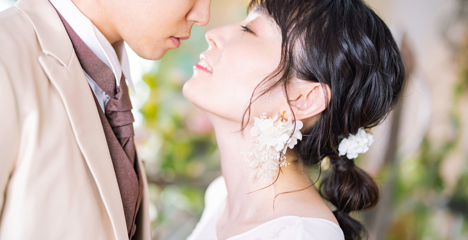 白いウェディングドレスを着た新婦がタキシード姿の新郎とキスをしている［モデル：たけべともこ］