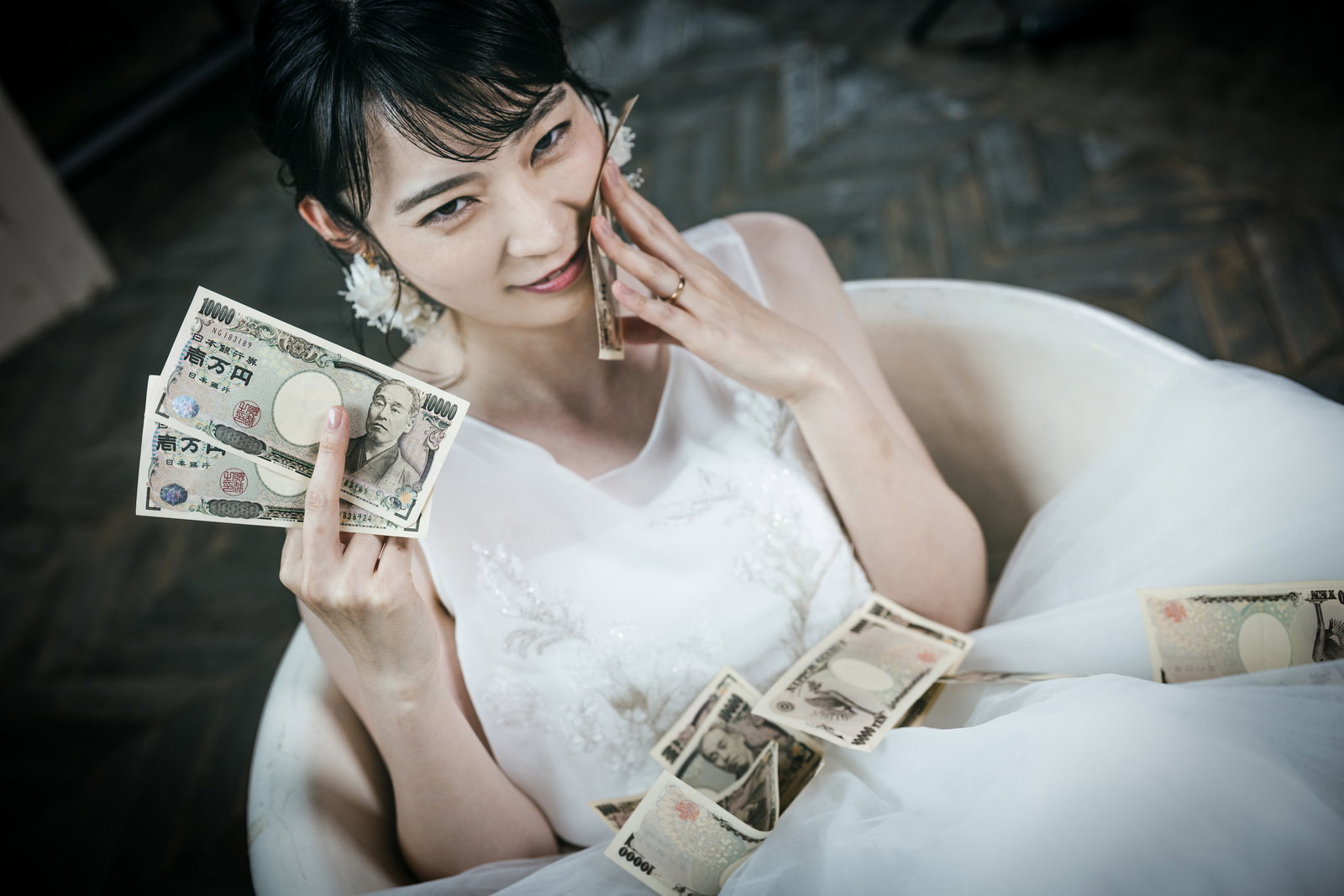 ウェディングドレス姿の女性が1万円札を持つ［モデル：たけべともこ］