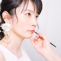 ウェディングドレス姿で唇のメイク中の花嫁の写真