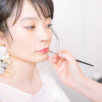 ウェディングドレス姿で口元を直す花嫁のメイクの写真