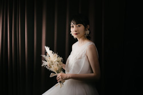 ブーケを持って佇む新婦のウェディングドレス姿