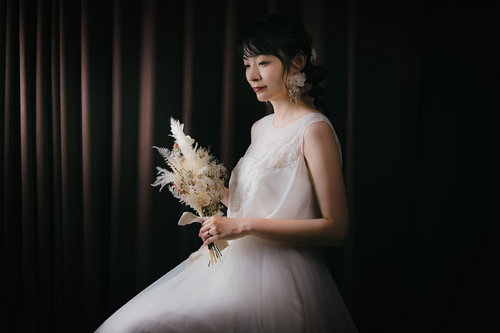 ドライフラワーのブーケを持ったウェディングドレス姿の女性