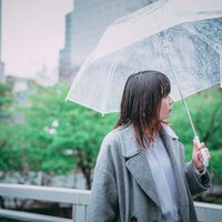 ビニール傘をさして歩く女性の写真