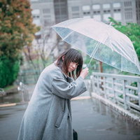 ビニール傘を差して辺りを警戒する女性の表情の写真