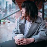 テラス席でコーヒーを飲みながら雨を眺める憂鬱女子の写真