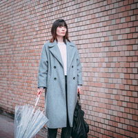 呆然と立ち尽くす雨宿り中の女性とレンガ壁の風景の写真