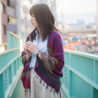 歩道橋の上で立ち止まり景色を眺める若い女性の写真
