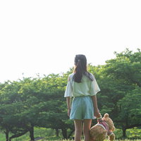 テディベアを離さない娘の後ろ姿、公園で大切に抱きしめるの写真