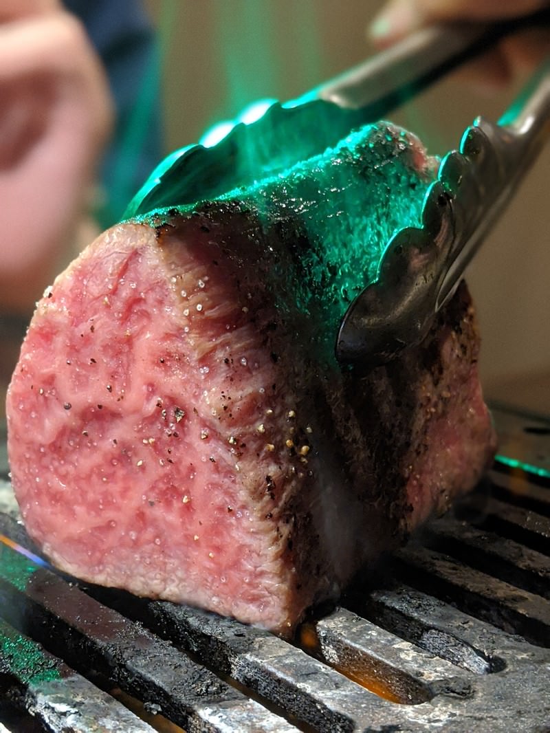 Raw Thick-Cut Meat Held by Tongs on a Grill — Free Stock Photo - PAKUTASO