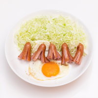 白い皿に盛られた目玉焼きとウインナーのおかずの写真