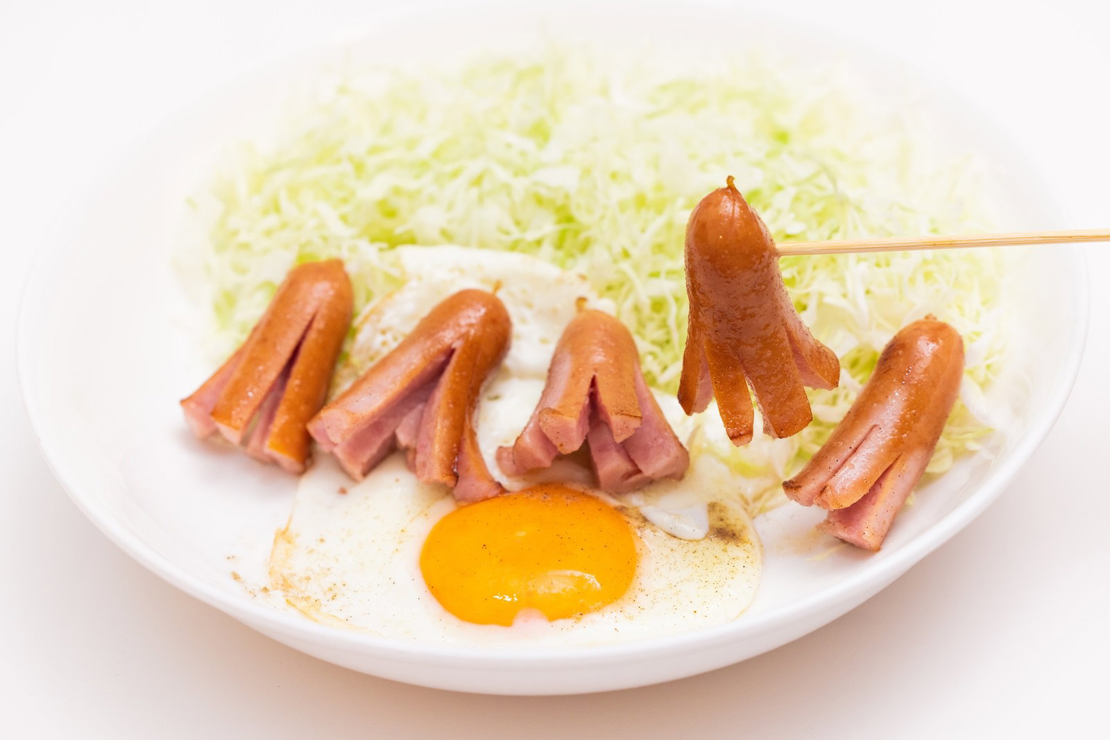 白い皿に盛られた目玉焼きとタコさんウインナー、キャベツの千切り