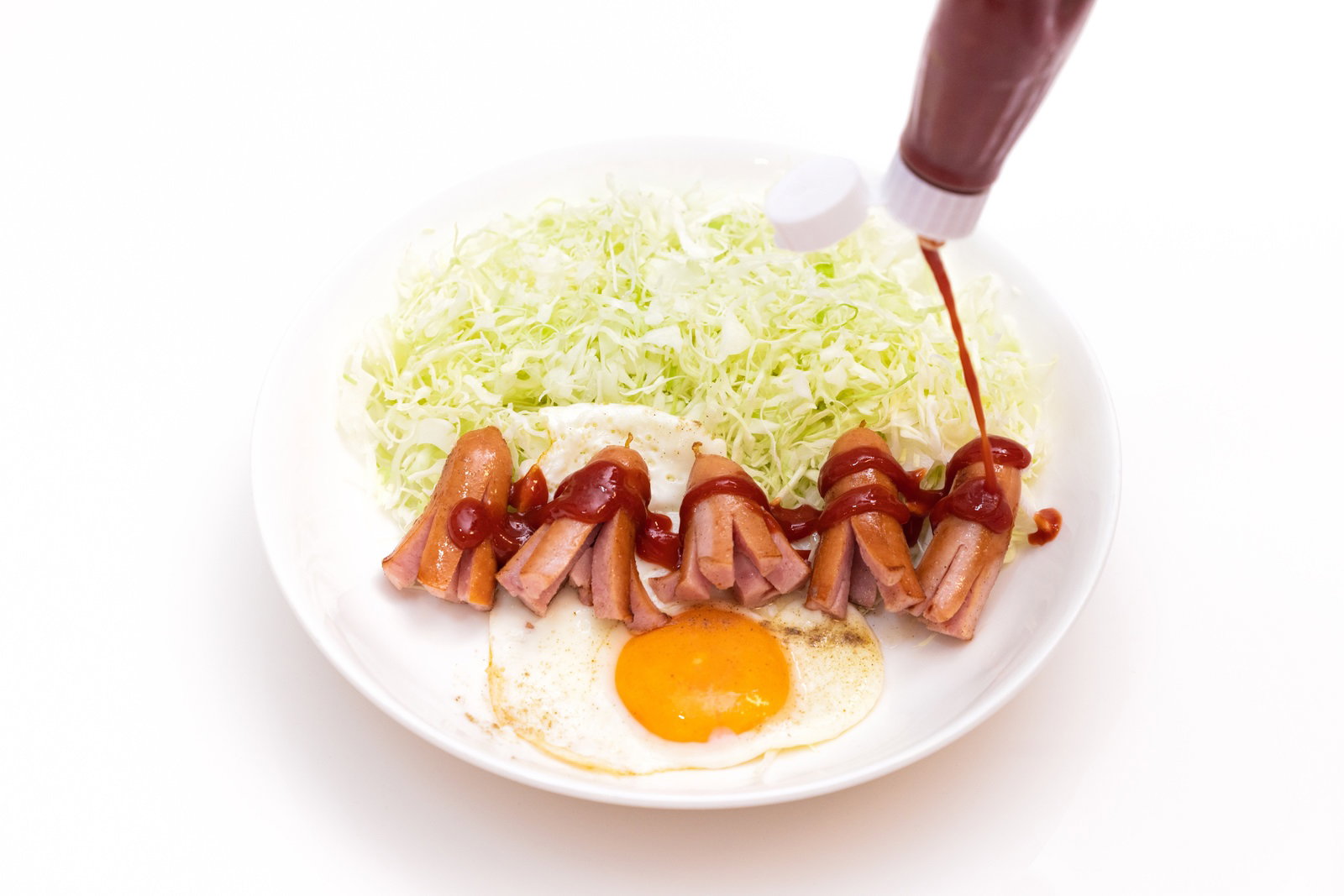 白いお皿に盛られたタコさんウインナーにケチャップをかけている様子