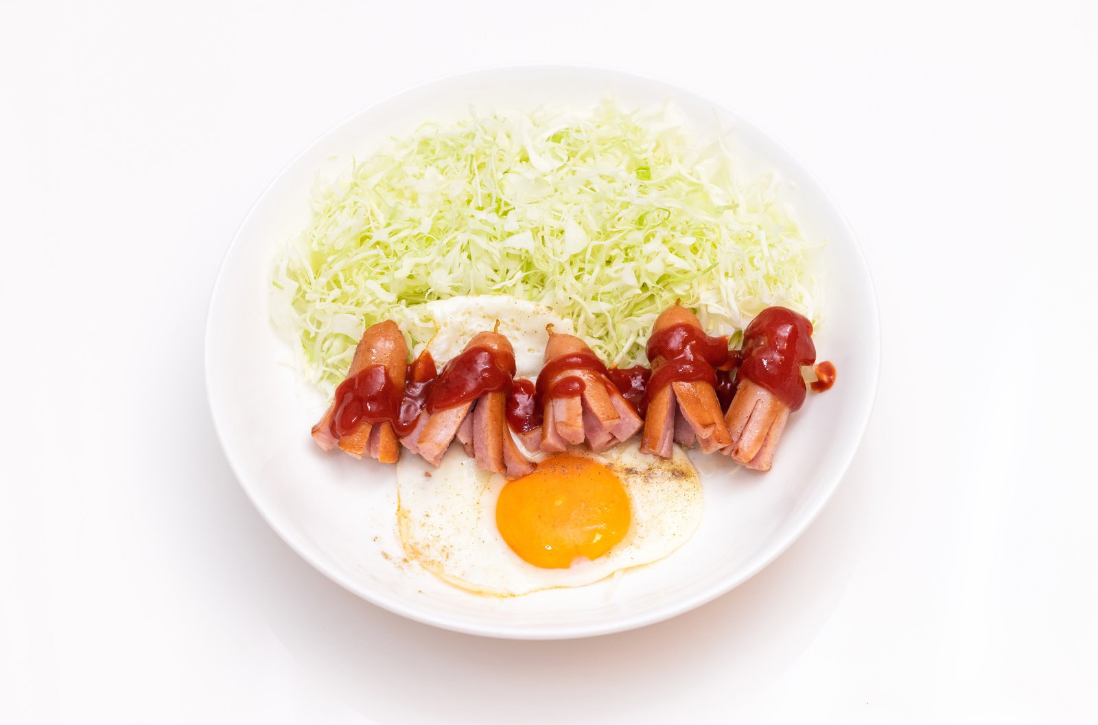 白い皿に盛られたケチャップがかかったタコさんウインナーと目玉焼き、キャベツの千切り
