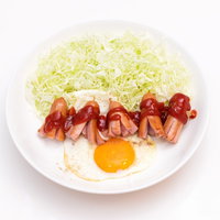 白い皿に盛られたケチャップがかかったタコさんウインナーと目玉焼きの写真