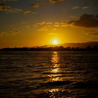 夕焼けに染まる工業港の景観と大型クレーン群の写真