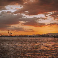 夕焼けの工業港とクレーンのシルエットの写真