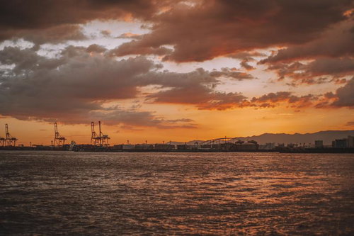 夕焼けの工業港とクレーンのシルエット