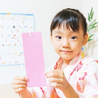 七夕の短冊に願いごとを書く浴衣姿の女の子の写真