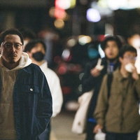 中華街の繁華街で肉まん食べ歩きのお店を探す男性の写真
