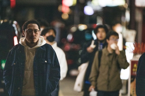 中華街の繁華街で肉まん食べ歩きのお店を探す男性