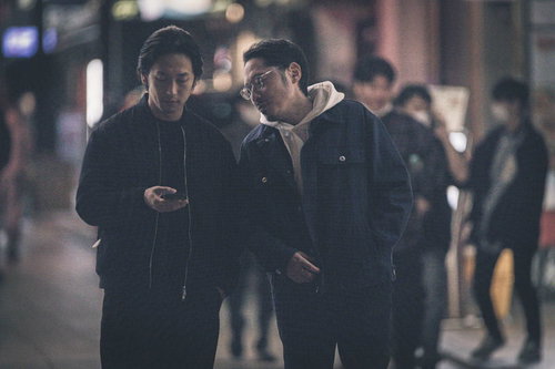 依頼者からの指示を確認する探偵二人がスマートフォンで情報共有