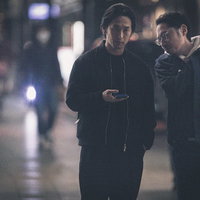 夜の繁華街で尾行対象を確認する探偵ふたりの写真