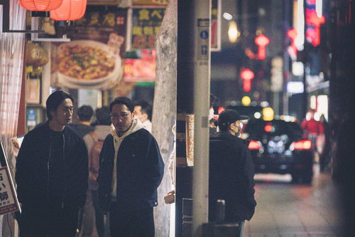 夜の繁華街の片隅で張り込みを続ける二人の探偵