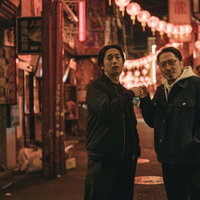 繁華街の夜間で決めるグータッチする二人の男性の写真