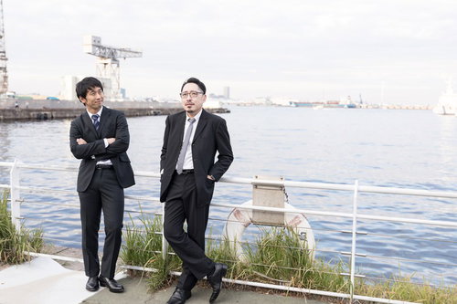 港の柵で海を眺める2人の刑事が事件捜査で立ち止まる