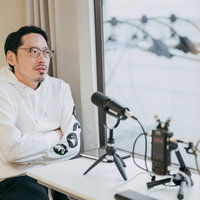 マイクの前で腕組みして収録中の男性のポッドキャスト配信をするイケオジの写真