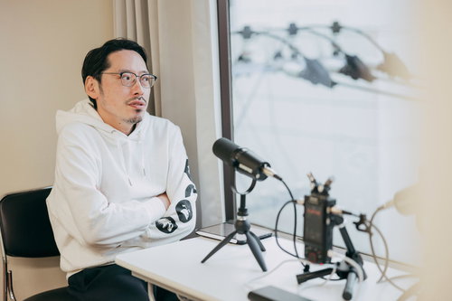 ポッドキャスト収録中のマイク前で話すMC男性