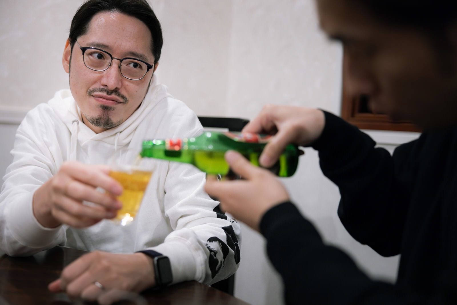 眼鏡をかけた上司が瓶ビールを注がれながらチェックしている様子［モデル：ゆうせい］