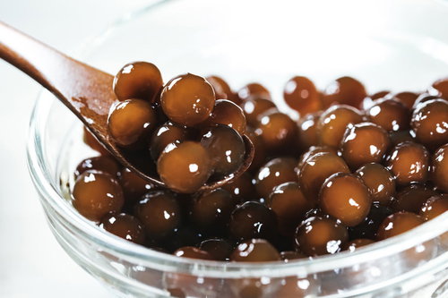 ガラス容器に入ったブラックタピオカの実とスプーン