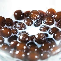 透明なグラスに入ったミルク入りブラックタピオカの写真