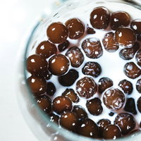 グラスに沈殿したブラックタピオカとミルクの写真