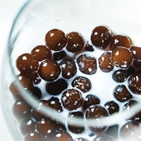 飲みきれないグラスに沈んだブラックタピオカミルクティの写真