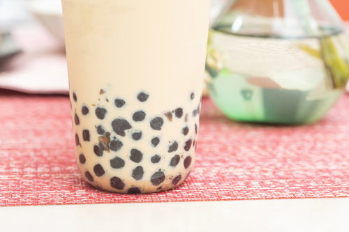 透明なグラスのミルクティーに沈殿するタピオカ