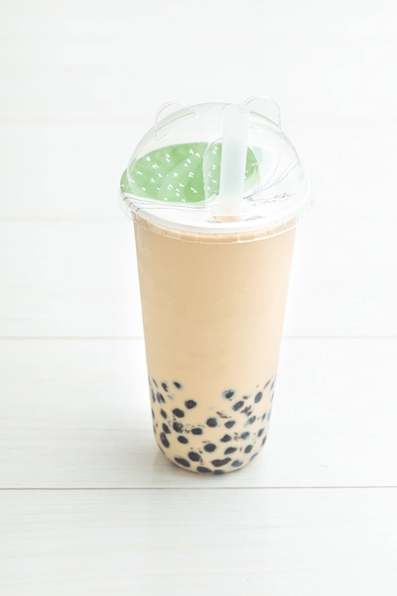 透明カップに入ったタピオカミルクティ、ベージュ色のミルクティーと黒いタピオカ