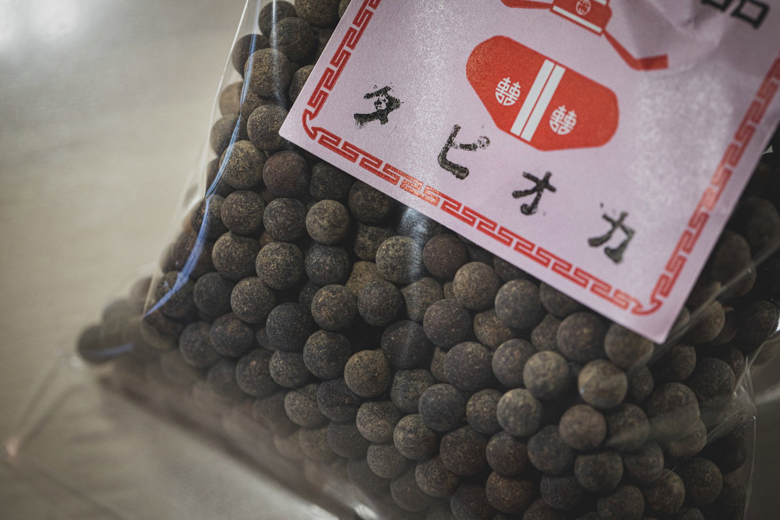 赤いラベルが貼られた透明な袋に詰まった黒い球形のタピオカ粒