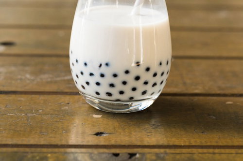 透明なグラスの底に沈殿するブラックタピオカのミルクティ