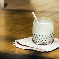 白いコースターに置いたタピオカミルクティの写真