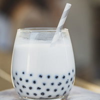 透明なグラスに入ったタピオカミルクティーの写真