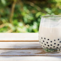 ブラックタピオカがたっぷり入ったミルクティのグラスの写真