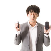 加熱式タバコの使い方を説明するスーツ姿の男性の写真