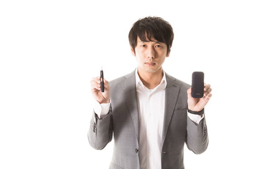 加熱式タバコの使い方を説明するスーツ姿の男性